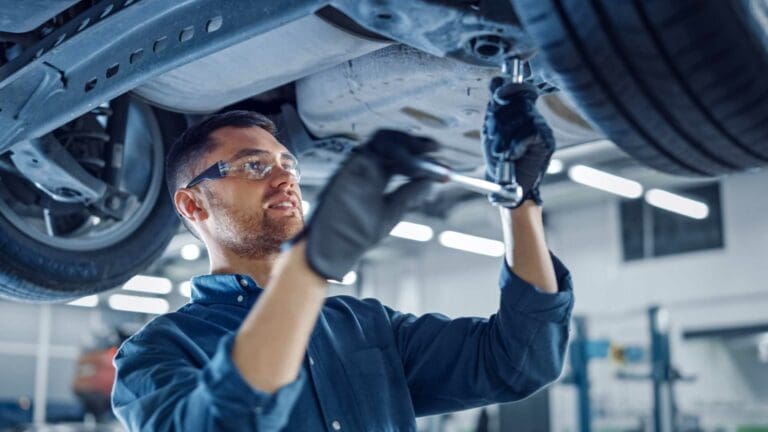 Repair technician working on the underside of a vehicle